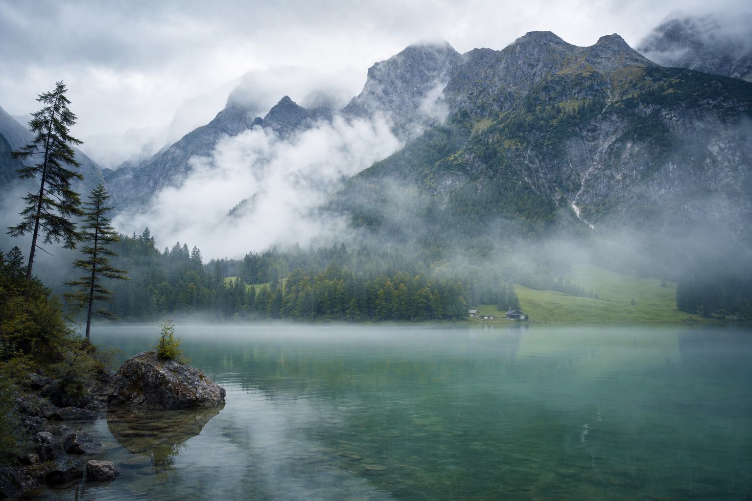 Alpensee unter Berghängen in der Morgensonne